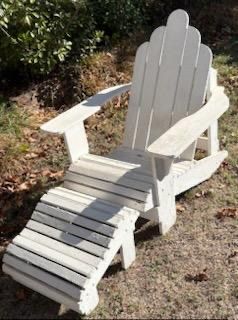 White wooden Adirondack chair with matching slatted ottoman footrest, showing light outdoor wear.