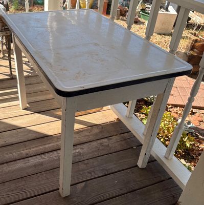 Vintage white enamel-top kitchen table with black trim and a painted wooden base.