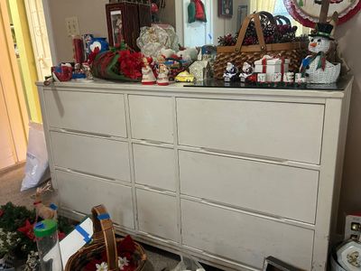 White painted mid-century nine-drawer dresser topped with holiday decor, figurines, and a woven basket.