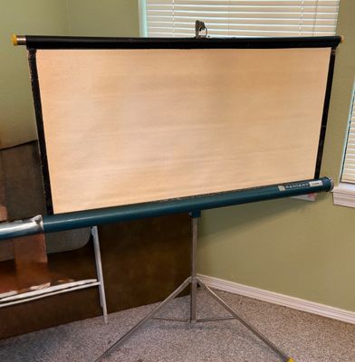 Vintage Radiant portable projection screen on a metal tripod stand, showing light surface discoloration to the fabric.