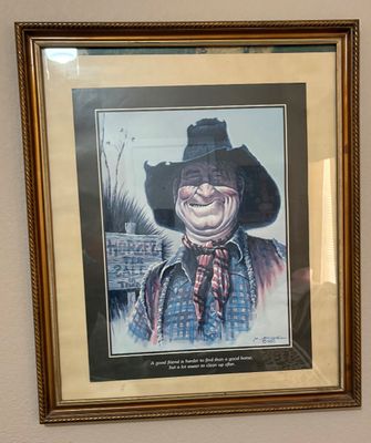 Framed Western art print by M. Scovel dated 1983, featuring a smiling cowboy caricature with humorous text, presented in an ornate...