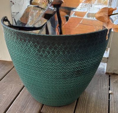 Large teal and black textured plastic planter pot sitting on a wooden deck.