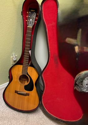 Vintage Yamaha acoustic guitar resting inside a red plush-lined hard shell case.