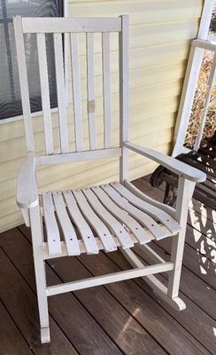 White wooden porch rocking chair featuring a slatted seat and high vertical slat back.