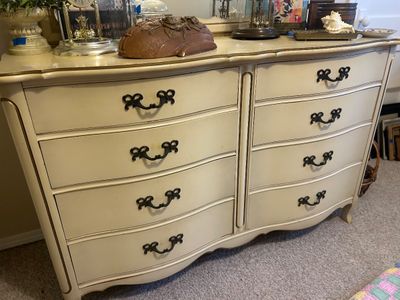 French Provincial style double dresser in an off-white finish with gold trim accents and dark metal bail handles.