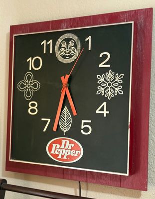 Vintage Dr Pepper square wall clock with a maroon faux-wood grain border and mid-century graphic symbols.