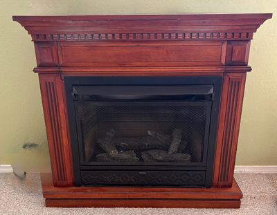 Freestanding electric fireplace featuring a cherry-finished wooden mantel with fluted columns and dental molding details.