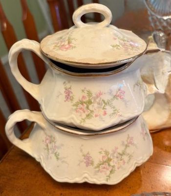 Vintage porcelain sugar bowl and creamer set with delicate pink floral patterns and gold rim accents.