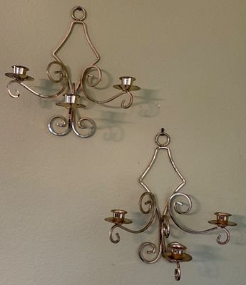 Pair of vintage brass three-light wall sconces with scrolled wrought detailing and top hanging rings.