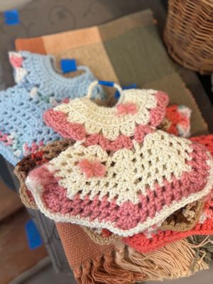 Collection of handmade miniature crocheted dress ornaments and pot holders in various pastel colors.