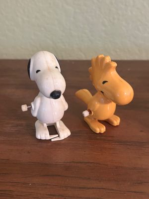 Vintage plastic wind-up toys of Peanuts characters Snoopy and Woodstock, featuring classic mechanical walking actions.