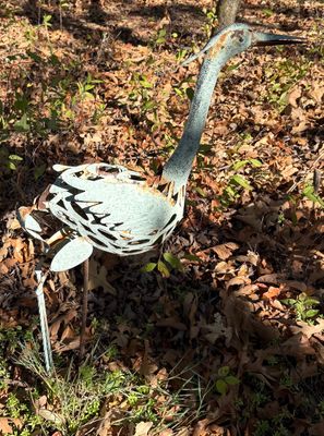 Weathered metal heron garden sculpture with a verdigris finish and openwork body detail.