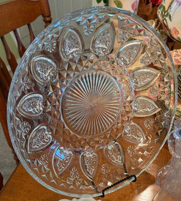 Vintage pressed clear glass serving platter featuring intricate starburst, diamond cut, and floral heart motifs, displayed on a black...