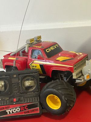 Vintage Tyco R/C red Chevy off-road monster truck with matching transmitter remote, showing play wear and light dust.