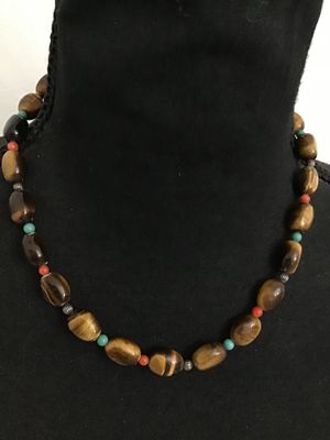 Sale Photo Thumbnail #20: A beaded gemstone necklace featuring smooth, polished tiger's eye oval beads accented with small turquoise and red/coral-tone spacer beads and silver-tone fluted metal spacers. Finished with a decorative silver-tone toggle closure clasp. In good pre-owned