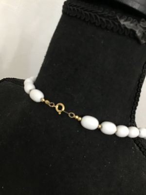 Sale Photo Thumbnail #265: A classic strand necklace featuring smooth, glossy white oval beads spaced with small gold-tone seed beads. Secured with a traditional gold-tone spring ring clasp. Appears to be in good vintage condition with minimal surface wear.