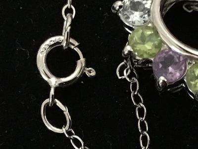 Sale Photo Thumbnail #140: A sterling silver heart-shaped pendant necklace featuring a reversible design. One side is adorned with multi-color round faceted gemstones including amethyst, peridot, citrine, garnet, and blue topaz, while the reverse side features a halo of uniform lig