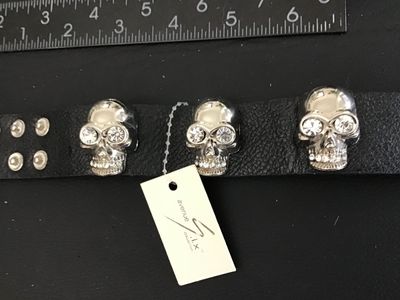 Sale Photo Thumbnail #54: Avenue Six Collection black textured leather or faux-leather cuff bracelet featuring three silver-tone metallic skulls set with clear rhinestone eyes and teeth accents. Secured with double snap closure. Measures approximately 8.5 to 9 inches long total. I