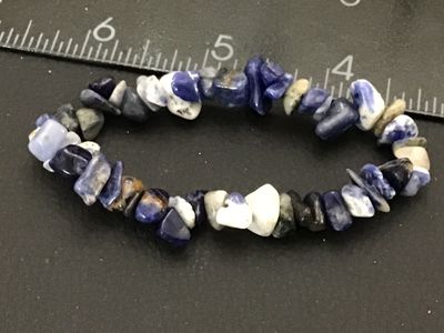 Sale Photo Thumbnail #132: Elastic stretch bracelet featuring polished blue, white, and grey natural stone chips, likely sodalite or lapis. Measures approximately 2.5 inches across unstretched. Good pre-owned condition with no visible damage.