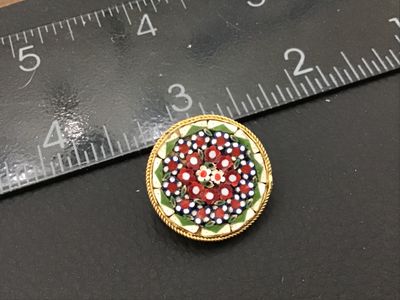 Sale Photo Thumbnail #152: Round vintage Italian micro mosaic pin or brooch featuring a colorful floral pattern with red, white, blue, and green glass tesserae set in a gold-tone twisted wire frame. Pin measures approximately 1 inch in diameter. Features a classic C-clasp/pin back.