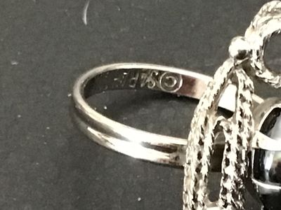 Sale Photo Thumbnail #108: Vintage Sarah Coventry silver-tone costume ring featuring a dark oval cabochon stone (hematite style) set within an ornate, textured swirl motif setting. Marked ©SARAH COV on the inner band. Features an adjustable band construction. Good vintage conditio