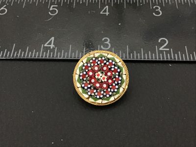 Sale Photo Thumbnail #151: Round vintage Italian micro mosaic pin or brooch featuring a colorful floral pattern with red, white, blue, and green glass tesserae set in a gold-tone twisted wire frame. Pin measures approximately 1 inch in diameter. Features a classic C-clasp/pin back.