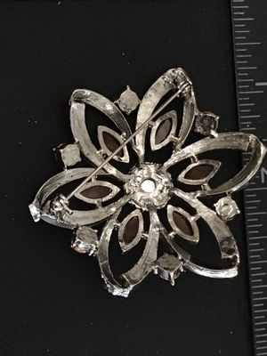 Sale Photo Thumbnail #35: Silver-tone floral pin or brooch set with light pink and amber marquise-cut and round rhinestones. Measures approximately 2.25 inches across. Features a textured back and pin-back clasp mechanism. Good pre-owned condition with all stones intact.