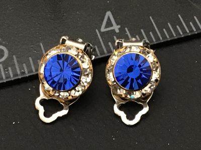 Sale Photo Thumbnail #113: Pair of vintage clip-on earrings featuring round facetted bright blue rhinestones surrounded by a halo of clear crystals. Set in gold-tone metal housings with silver-tone clip backs. Each earring measures approximately 3/4 inch long. In good vintage condi