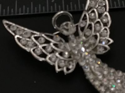 Sale Photo Thumbnail #225: Silver-tone metal brooch designed in the shape of a winged guardian angel with a halo, densely set with clear rhinestones throughout the body and openwork wings. Features a standard pin back with rollover safety clasp. Measures approximately 2.25 inches i