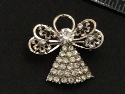 Sale Photo Thumbnail #213: Silver-tone metal brooch featuring an angel design set with clear rhinestones on the gown and openwork filigree style wings. Back features a roll-over safety clasp mechanism. Measures approximately 1 inch wide. In good pre-owned condition with all stones 