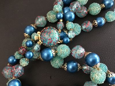 Sale Photo Thumbnail #59: A mid-century vintage double strand necklace featuring a combination of bright blue satin glass pearls, textured light blue sugar beads, and clear glass beads with red and gold foil speckles. Includes filigree metal bead caps and a decorative box clasp fe