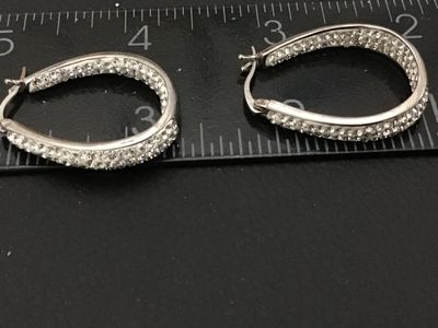 Sale Photo Thumbnail #94: Pair of silver-tone oval hoop earrings set with clear pavé rhinestones/crystals. Features latch-back closures. Earrings measure approximately 1 inch in length as shown against the scale. Good pre-owned condition with all stones intact.