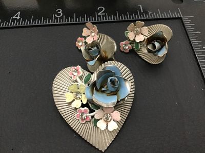 Sale Photo Thumbnail #266: A vintage Coro costume jewelry set featuring a heart-shaped brooch pin and matching clip-on earrings. Design features silver-tone ribbed metal hearts adorned with colorful enamel flowers (blue, pink, yellow) and clear rhinestone accents. The clip-on earri