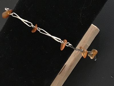 Sale Photo Thumbnail #82: Handcrafted silver tone wire-wrapped link bracelet featuring natural amber-colored chip beads spaced along twisted wire links. Measures approximately 7 to 7.5 inches in length with a spring ring closure. Appears to be in good pre-owned condition with mino
