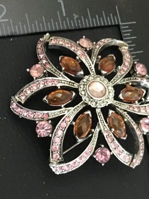Sale Photo Thumbnail #34: Silver-tone floral pin or brooch set with light pink and amber marquise-cut and round rhinestones. Measures approximately 2.25 inches across. Features a textured back and pin-back clasp mechanism. Good pre-owned condition with all stones intact.