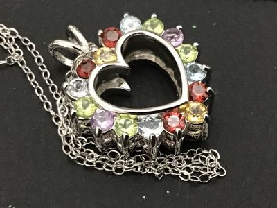 Sale Photo Thumbnail #142: A sterling silver heart-shaped pendant necklace featuring a reversible design. One side is adorned with multi-color round faceted gemstones including amethyst, peridot, citrine, garnet, and blue topaz, while the reverse side features a halo of uniform lig