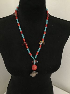 Sale Photo Thumbnail #7: Unique beaded strand necklace featuring turquoise-colored and red coral-tone beads interspersed with blown/cast glass horse head charms. Features a focal drop with a glass horse head, large red bead, and a stamped metal cross pendant. Includes a metal tog