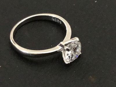Sale Photo Thumbnail #222: A sterling silver solitaire ring featuring a large round brilliant cut clear stone (likely cubic zirconia or simulated diamond) in a four-prong setting. The interior band is stamped "S925". Shown on a ring mandrel as a size 6. In good pre-owned condition 