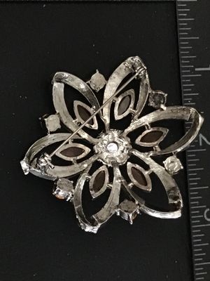 Sale Photo Thumbnail #36: Silver-tone floral pin or brooch set with light pink and amber marquise-cut and round rhinestones. Measures approximately 2.25 inches across. Features a textured back and pin-back clasp mechanism. Good pre-owned condition with all stones intact.