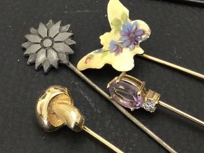 Sale Photo Thumbnail #122: Collection of four vintage stick pins featuring a variety of designs including an enameled floral butterfly, a gold-tone mushroom, a flower motif, and a pin set with a faceted purple stone (possibly amethyst or glass) and accent stone. Includes end caps o