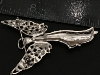 Sale Photo Thumbnail #226: Silver-tone metal brooch designed in the shape of a winged guardian angel with a halo, densely set with clear rhinestones throughout the body and openwork wings. Features a standard pin back with rollover safety clasp. Measures approximately 2.25 inches i