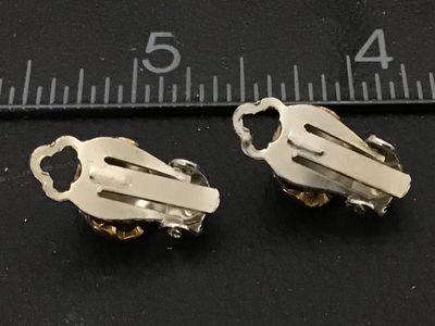 Sale Photo Thumbnail #115: Pair of vintage clip-on earrings featuring round facetted bright blue rhinestones surrounded by a halo of clear crystals. Set in gold-tone metal housings with silver-tone clip backs. Each earring measures approximately 3/4 inch long. In good vintage condi
