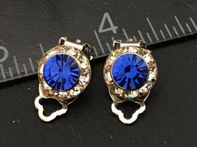 Sale Photo Thumbnail #114: Pair of vintage clip-on earrings featuring round facetted bright blue rhinestones surrounded by a halo of clear crystals. Set in gold-tone metal housings with silver-tone clip backs. Each earring measures approximately 3/4 inch long. In good vintage condi