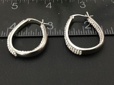 Sale Photo Thumbnail #93: Pair of silver-tone oval hoop earrings set with clear pavé rhinestones/crystals. Features latch-back closures. Earrings measure approximately 1 inch in length as shown against the scale. Good pre-owned condition with all stones intact.