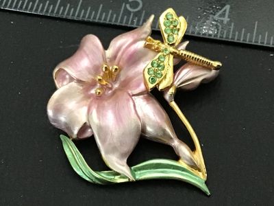 Sale Photo Thumbnail #128: A vintage gold-tone costume jewelry brooch featuring a pink and white enamel lily flower with a green enameled leaf stem and a green rhinestone-accented dragonfly resting on the petals. The back is signed 'AS ©' and features a secure pin stem and rollove