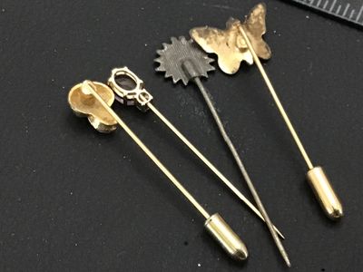 Sale Photo Thumbnail #125: Collection of four vintage stick pins featuring a variety of designs including an enameled floral butterfly, a gold-tone mushroom, a flower motif, and a pin set with a faceted purple stone (possibly amethyst or glass) and accent stone. Includes end caps o