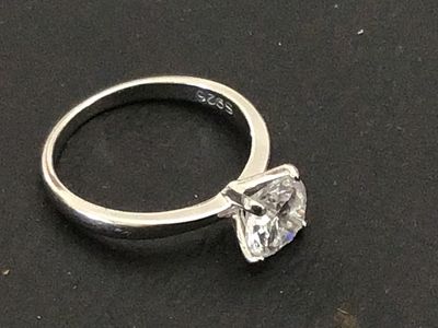 Sale Photo Thumbnail #220: A sterling silver solitaire ring featuring a large round brilliant cut clear stone (likely cubic zirconia or simulated diamond) in a four-prong setting. The interior band is stamped "S925". Shown on a ring mandrel as a size 6. In good pre-owned condition 