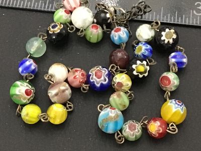 Sale Photo Thumbnail #117: A colorful vintage necklace featuring handcrafted Venetian Murano Millefiori art glass beads in various floral and patterned designs, connected by brass tone metal wire link loops. Includes a variety of vibrant glass beads in shades of blue, yellow, green