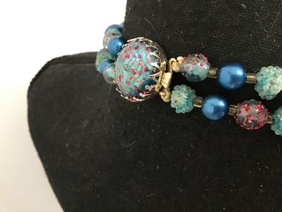 Sale Photo Thumbnail #62: A mid-century vintage double strand necklace featuring a combination of bright blue satin glass pearls, textured light blue sugar beads, and clear glass beads with red and gold foil speckles. Includes filigree metal bead caps and a decorative box clasp fe