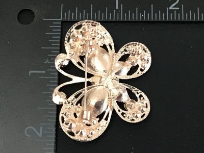 Sale Photo Thumbnail #47: A gold-tone butterfly pin/brooch featuring teardrop emerald green faceted glass stones, clear rhinestones, and iridescent aurora borealis rhinestones along the antennae and center body. Features openwork filigree details on the wings and a standard pin ba